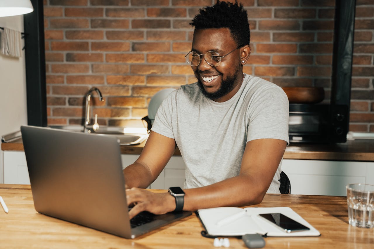 African American man smiling while working remotely on laptop from home office