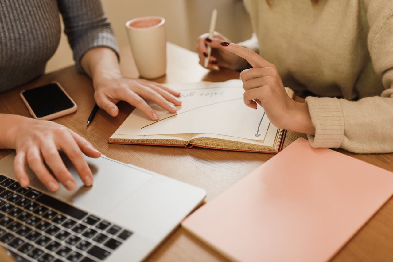 Close-up of colleagues working together with a laptop and notes at a desk.