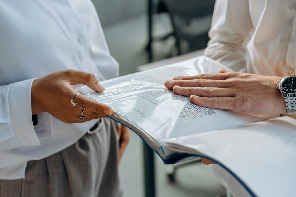 Two professionals examining business documents during a meeting indoors.